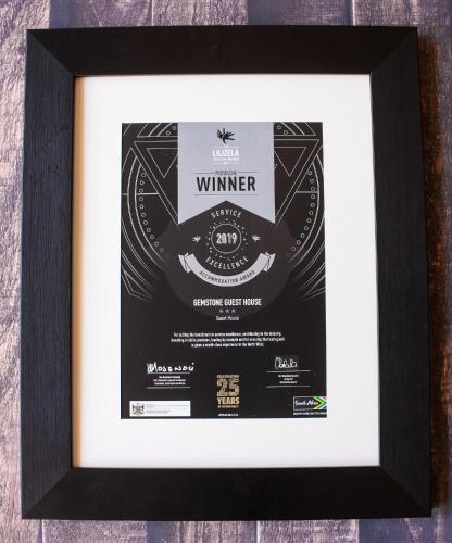 a framed picture of a wine poster in a black frame at Gemstone Guest House in Klerksdorp