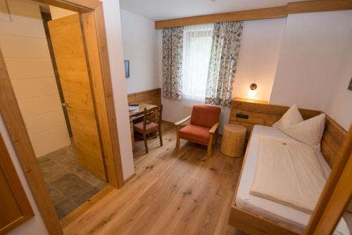 a small room with a bed and a desk at Hotel Brunnwirt in Weissbriach
