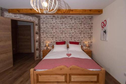een slaapkamer met een houten bed met een bakstenen muur bij Gîte L'Ecrin du Ried "COSY" in Artolsheim