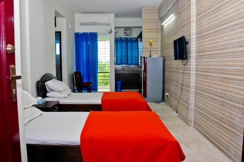 シレットにあるSaanha Windtripのベッド2台と赤いベンチ付きのホテルルームです。