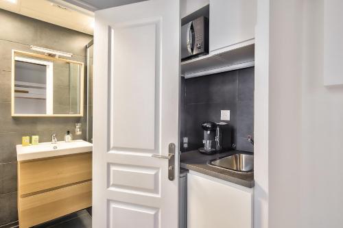 une porte blanche menant à une salle de bains avec lavabo. dans l'établissement Lovely Mezzanine Studio in the Heart of Paris 3M, à Paris