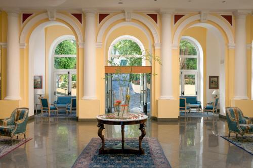 a lobby with a table and chairs and windows at Imperial Hotel Tramontano in Sorrento