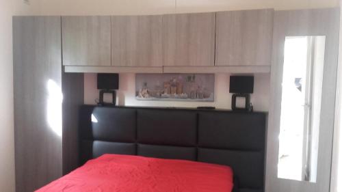 - une chambre avec un lit rouge et des placards en bois dans l'établissement Maison ronde atypique et unique, à Torreilles