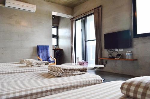 a room with three beds and a flat screen tv at Taitung Jia Lulan Tribal in Taitung City