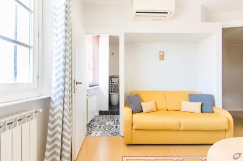 a living room with a yellow couch and a window at Le Camere Pietrasantine - Centro Storico in Pietrasanta