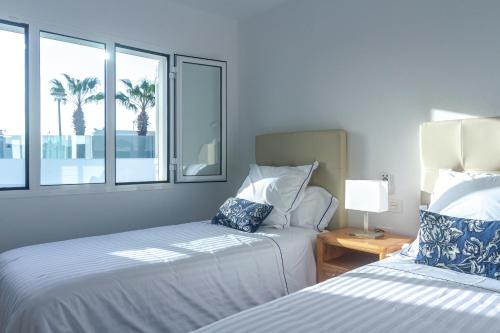 a bedroom with two beds and a window with palm trees at Rooms & Suites Princesa Mercedes in Puerto del Carmen