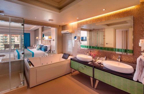 a bathroom with two sinks and a tub and a bedroom at Premier Le Reve Hotel & Spa Sahl Hasheesh - Adults Only 16 Years Plus in Hurghada