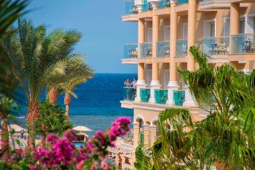 a building with palm trees and the ocean in the background at Premier Le Reve Hotel & Spa Sahl Hasheesh - Adults Only 16 Years Plus in Hurghada
