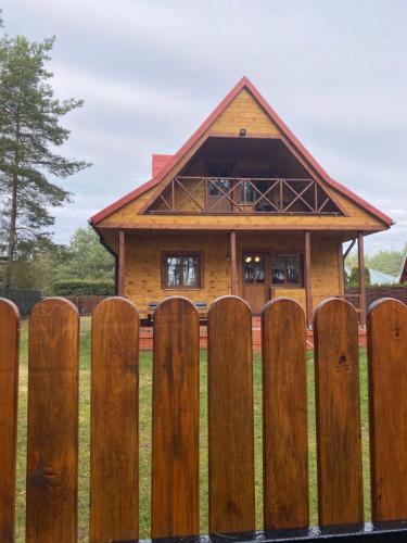 a wooden fence with a house behind it at Domek letniskowy w Puszczy Augustowskiej z sauną i balią in Ateny