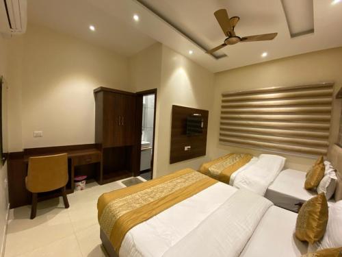 a bedroom with two beds and a desk and a television at Hotel Blossom Inn in Amritsar