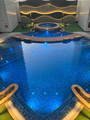 duży basen z niebieskimi światłami w budynku w obiekcie Bahrain bay studio w mieście Manama