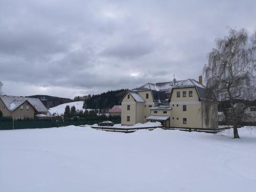 a house with snow on the ground in front of it at Apartmán Mocca in Kašperské Hory