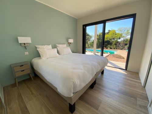 une chambre avec un grand lit et une grande fenêtre dans l'établissement VILLA ISULA by Intendance Excellency, à Sainte-Lucie de Porto-Vecchio