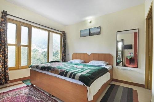 um quarto com uma cama e uma grande janela em Janardan Resort Pangot Nainital em Nainital