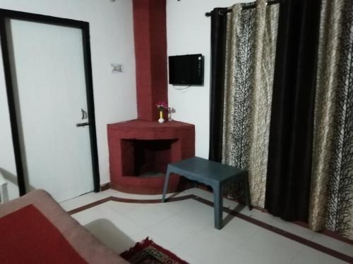 uma sala de estar com uma lareira vermelha e um banco azul em Janardan Resort Pangot Nainital em Nainital