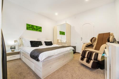 a bedroom with a large bed and a chair at Bada Bing Residence in Braşov