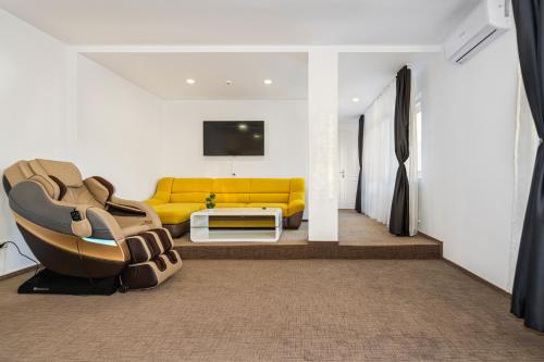 a living room with a yellow couch and a tv at Bada Bing Residence in Braşov