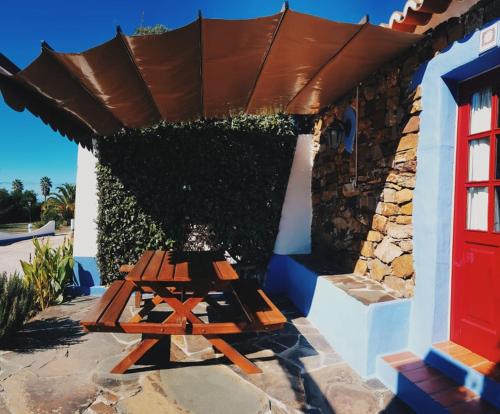 a picnic table in front of a building with a brown roof at Quinta do Sardanito de Tras in Zambujeira do Mar