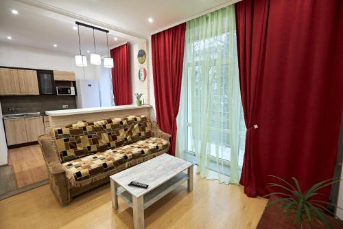 a living room with a couch and red curtains at Babylon Apartments On Soborna in Rivne