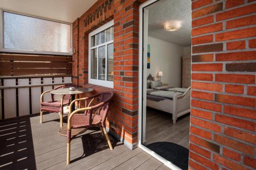 a balcony with a table and chairs and a brick wall at Ferienwohnung Nordseegrill in Borkum