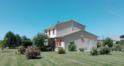 une maison blanche avec une cour fleurie dans l'établissement La Doucinière, à Polignac
