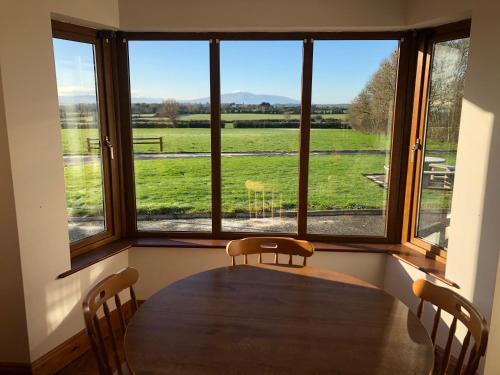 a table with chairs in a room with a large window at The Bungalow Knockreagh Farm Kilkenny R95AX50 in Callan