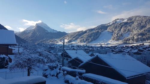 a village covered in snow with a mountain in the background at Résidence Julianna , trajets remontées mécaniques , livraison viennoiseries, piscine couverte in Morzine