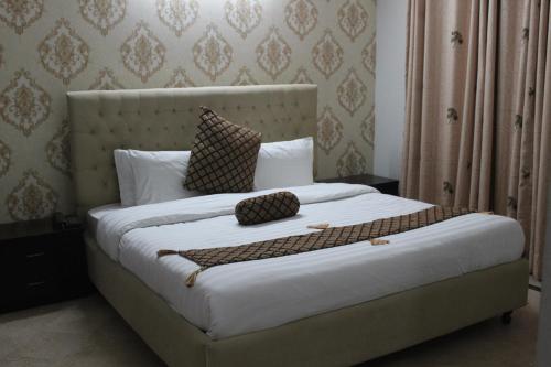 a bedroom with a large bed with white sheets and pillows at Royal Luxus Guest House in Islamabad