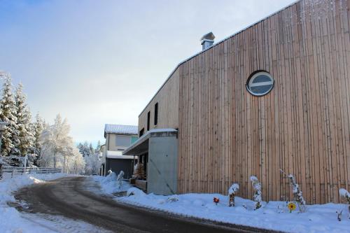 a building with snow on the ground next to a road at Apartment Monolith Black Forest in Schonach