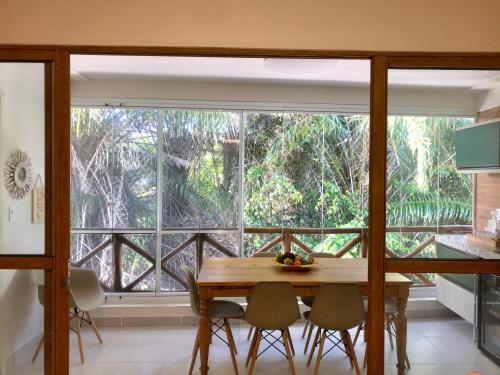a dining room with a table and a large window at Lindo apartamento Riverside Imbassaí in Imbassai