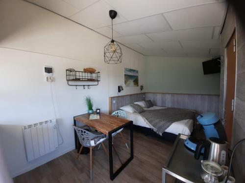 a small bedroom with a bed and a table at Beach Lodges Oostvoorne in Oostvoorne
