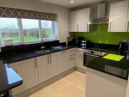 Una cocina con gabinetes blancos y encimeras negras. en Bagpuss Cottage Stunning 2 bedroom cosy cottage, en Witney