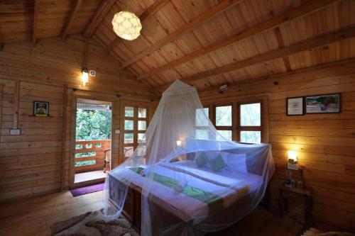 a bed in a wooden room with a mosquito net at Rainforest Munnar in Munnar