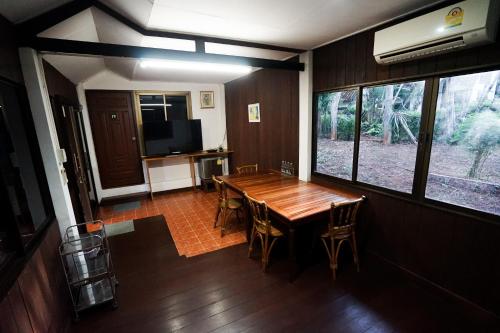 a dining room with a wooden table and chairs at Baan Chai Dan in Thong Pha Phum