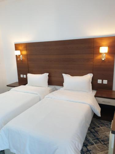 2 camas en una habitación de hotel con sábanas blancas en شقق سانتوريني الخاصة Santorini Private Apartments en Al Ula