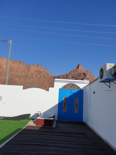 una puerta azul con una montaña en el fondo en شقق سانتوريني الخاصة Santorini Private Apartments en Al Ula
