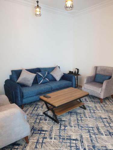 a living room with a blue couch and a coffee table at شقق سانتوريني الخاصة Santorini Private Apartments in AlUla