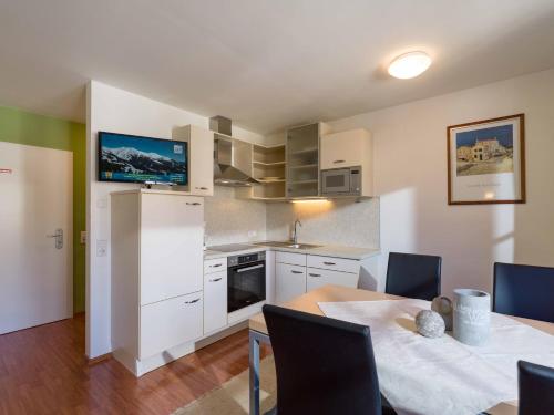 a kitchen with white cabinets and a table with chairs at Apartments Kolmblick in Gerlos