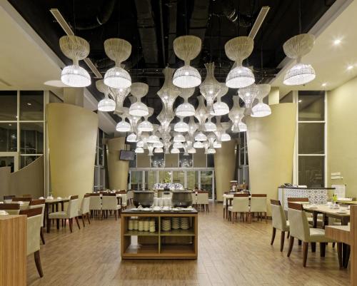 uma sala de jantar com mesas, cadeiras e lustres em Howard Johnson By Wyndham Pekalongan em Pekalongan