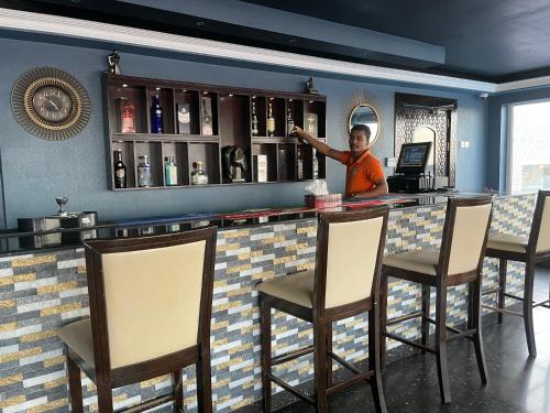 a man standing at a bar in a restaurant at Turtle Beach Resort in Al Ḩadd