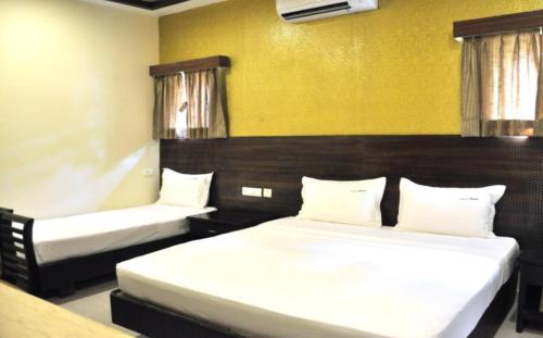 a bedroom with two beds and a yellow wall at Hotel Grand Parkway in Tambaram