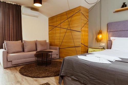 a bedroom with a bed and a couch at Семеен хотел АРИЗОНА in Pavel Banya