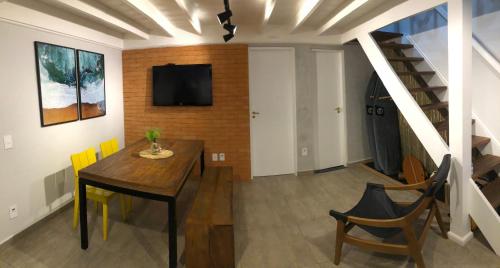 a dining room with a table and a tv on a wall at Lindo Flat em Maresias, 100m da Praia in Maresias