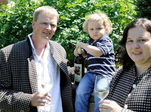 a man and a woman and a child holding a bottle of wine at Winzerhof - Gästehaus Stöger in Dürnstein