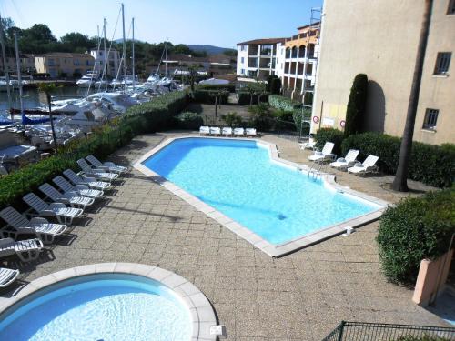 una gran piscina con tumbonas y un edificio en PCOGBLAN - Golfe de Saint-Tropez - T2 avec piscine vue marina, en Cogolin