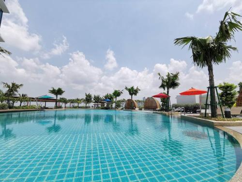 a pool at a resort with palm trees and umbrellas at Almas Puteri Harbour Nusajaya Suite room Exclusive Room 5 min to Legoaland by HomeSpace in Nusajaya