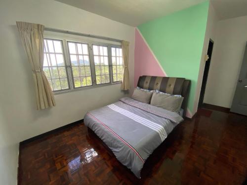 Cama en habitación con 2 ventanas en Unicorn Homestay @ Cameron Highland en Tanah Rata