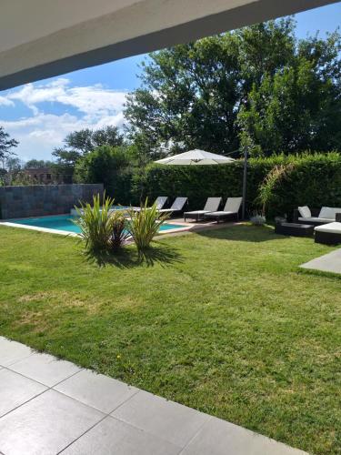 a yard with chairs and an umbrella and a pool at Cala hotel boutique in San Luis