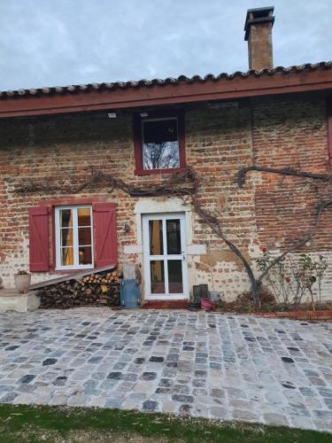 a brick house with red doors and a window at Le moulin de Varax in Saint-Paul-de-Varax