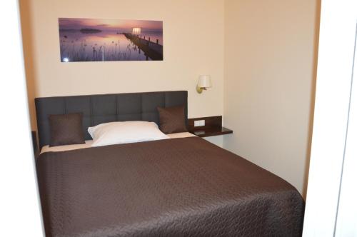 a bedroom with a bed with a painting on the wall at M2-Apartment in Szombathely